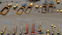 Trucks, boom lifts, and excavator submerged in water from flood