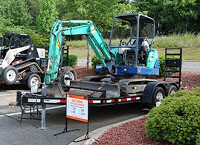 Excavator on a trailer with "for sale" sign